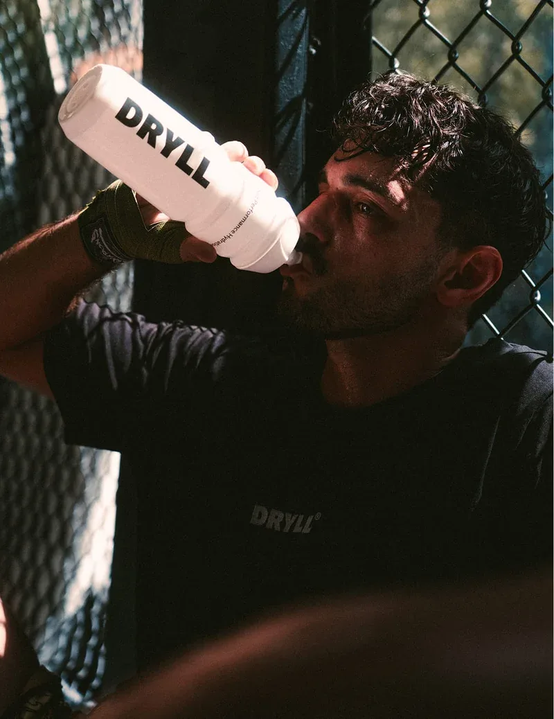 Fighter drinking from a DRYLL bottle
