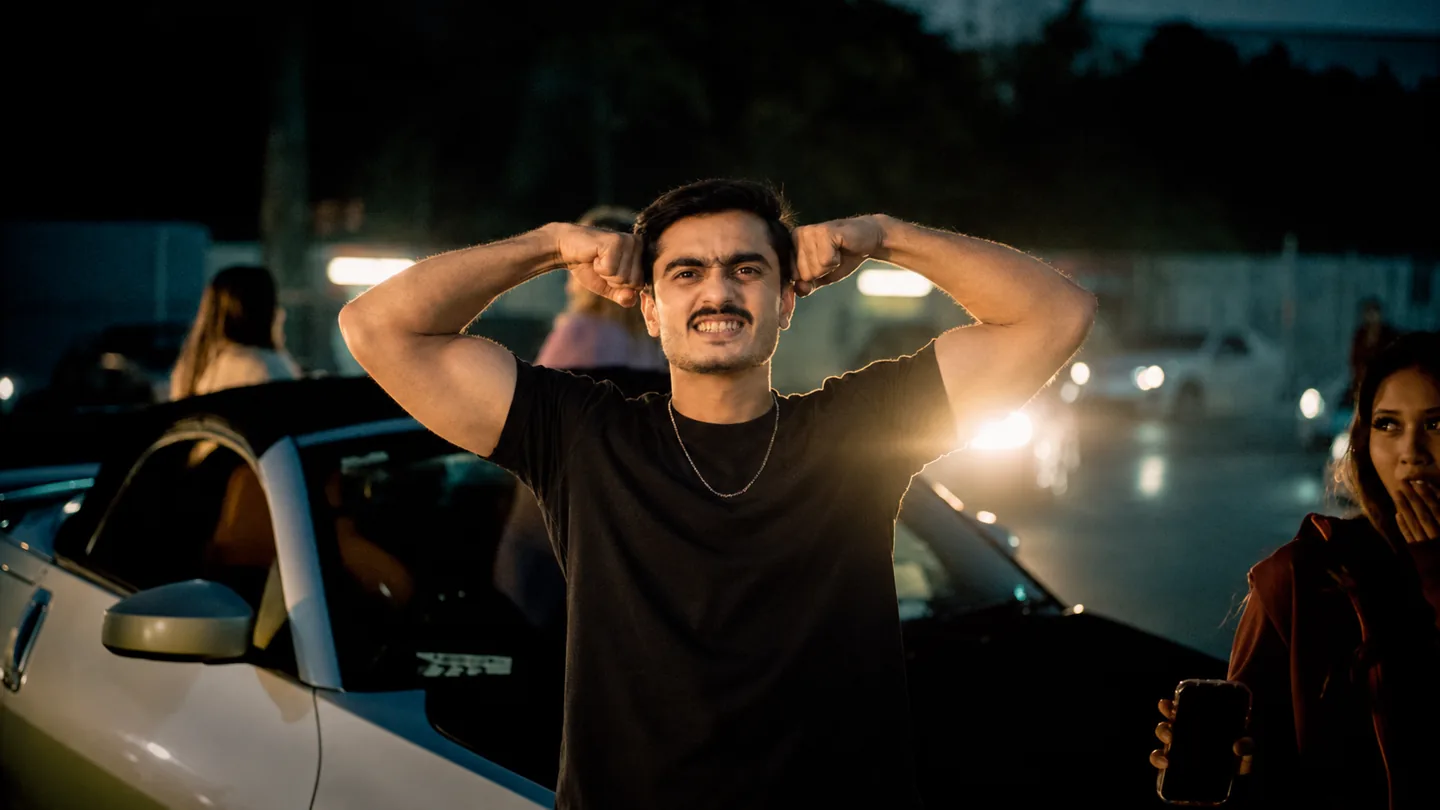 Man flexing in front of a car at night